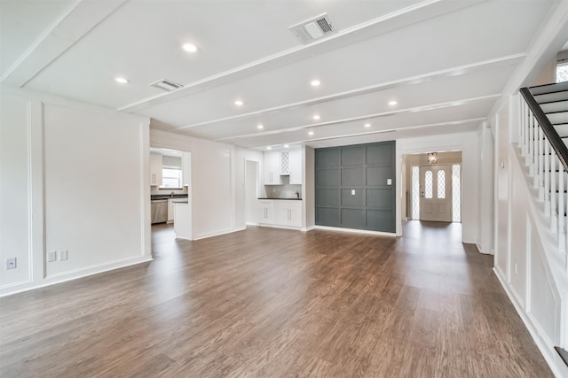 unfurnished living room with hardwood / wood-style floors and beamed ceiling