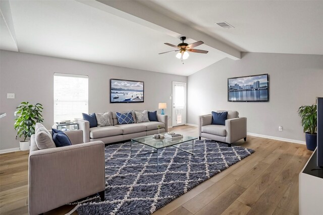 living room with ceiling fan, a healthy amount of sunlight, wood-type flooring, and vaulted ceiling with beams