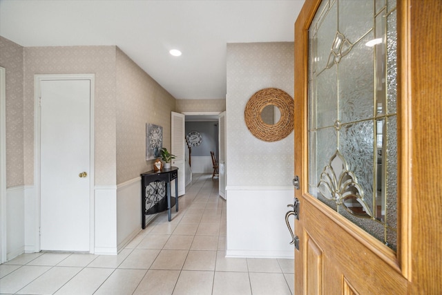 interior space with light tile patterned floors, a wainscoted wall, and wallpapered walls