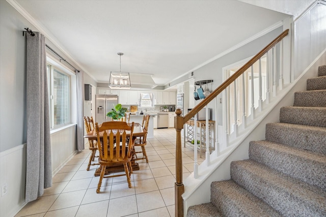 dining area with light tile patterned flooring, crown molding, and stairway