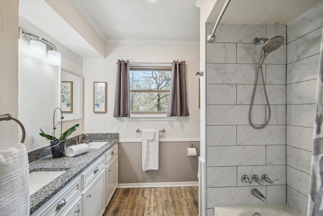 bathroom featuring double vanity, shower / bath combination, ornamental molding, a sink, and wood finished floors