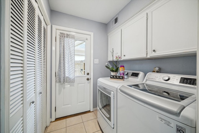 washroom featuring cabinet space, washing machine and dryer, light tile patterned floors, and visible vents