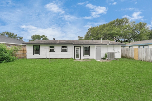 rear view of house with central AC and a lawn