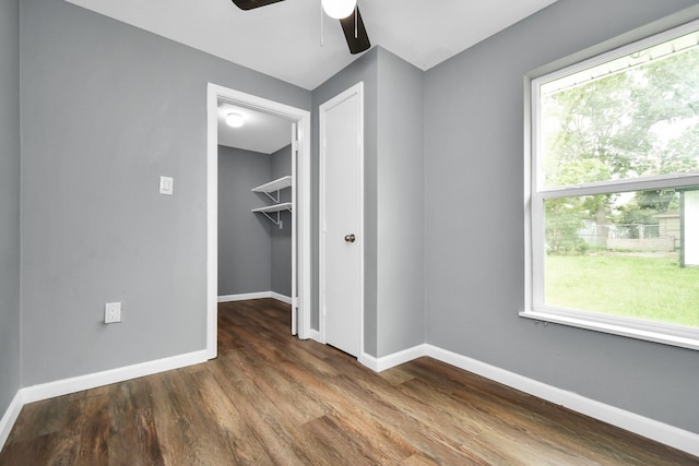 unfurnished bedroom with ceiling fan, a closet, wood-type flooring, and multiple windows