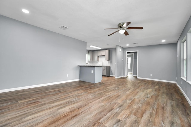 unfurnished living room featuring dark wood-type flooring and ceiling fan