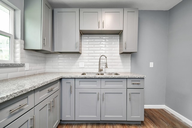 kitchen featuring gray cabinets, dark hardwood / wood-style floors, tasteful backsplash, sink, and light stone countertops