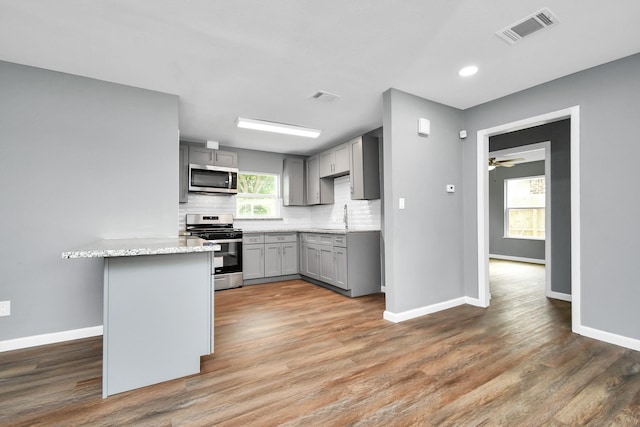 kitchen featuring gray cabinets, sink, backsplash, stainless steel appliances, and dark wood-type flooring