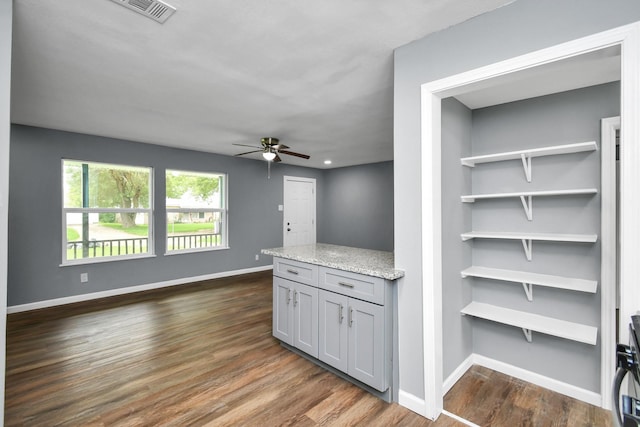 interior space with gray cabinetry, dark hardwood / wood-style flooring, light stone countertops, and ceiling fan