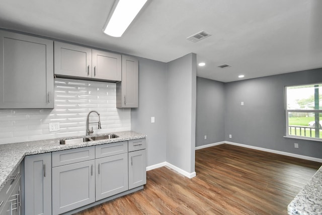 kitchen with dark hardwood / wood-style flooring, sink, gray cabinets, and light stone countertops