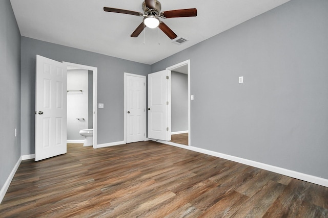 unfurnished bedroom featuring ceiling fan, ensuite bath, and dark hardwood / wood-style flooring