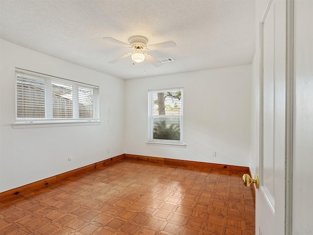 unfurnished room with ceiling fan and a textured ceiling