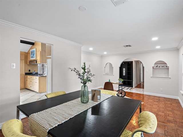 dining room featuring ornamental molding, arched walkways, visible vents, and baseboards