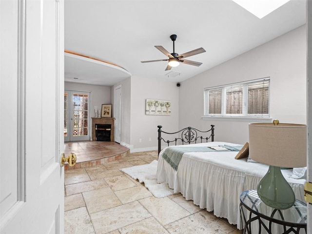 bedroom featuring baseboards, a tiled fireplace, stone tile floors, a ceiling fan, and lofted ceiling