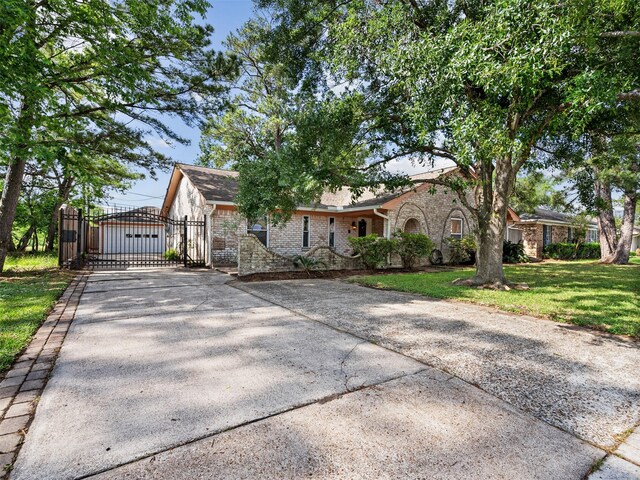 single story home featuring a gate, brick siding, a front yard, and concrete driveway