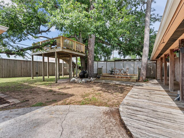 view of yard featuring a deck, a patio area, and a fenced backyard