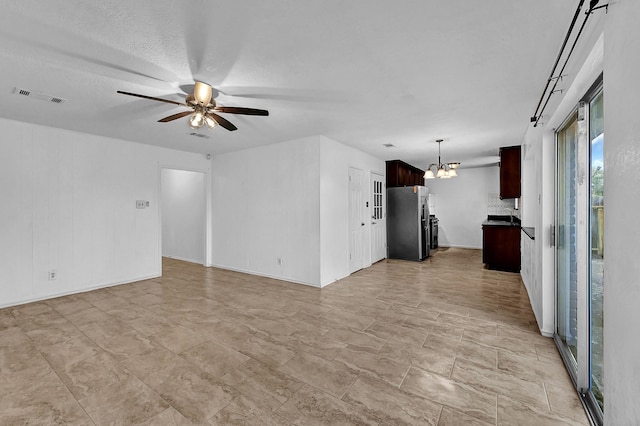 unfurnished living room with ceiling fan with notable chandelier and a textured ceiling