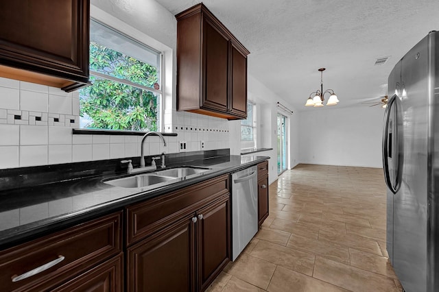 kitchen with appliances with stainless steel finishes, decorative light fixtures, sink, decorative backsplash, and a notable chandelier