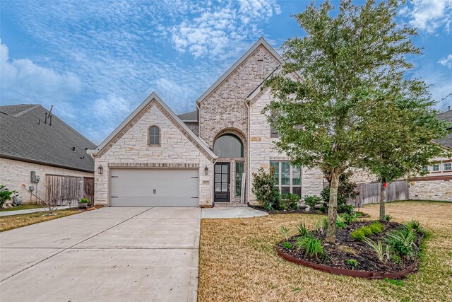 french country inspired facade featuring a garage and a front lawn