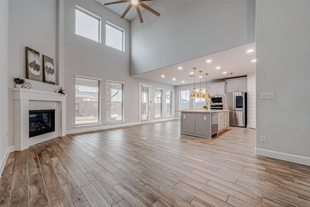 unfurnished living room with baseboards, a glass covered fireplace, and light wood-style floors