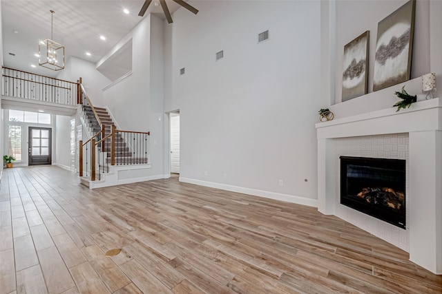 unfurnished living room featuring stairs, visible vents, baseboards, and wood finished floors