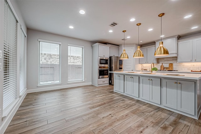 kitchen featuring visible vents, decorative backsplash, stainless steel appliances, light countertops, and light wood-type flooring