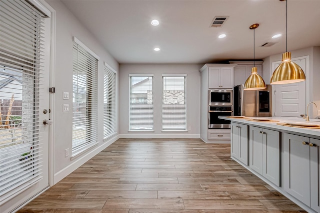 kitchen with stainless steel appliances, decorative light fixtures, light wood-style flooring, and recessed lighting