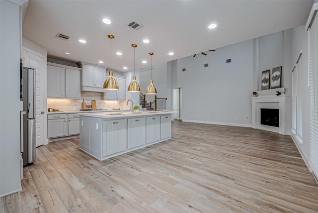 kitchen featuring a fireplace, visible vents, light countertops, and backsplash