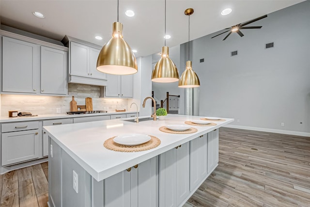 kitchen featuring a sink, light countertops, gas cooktop, and visible vents