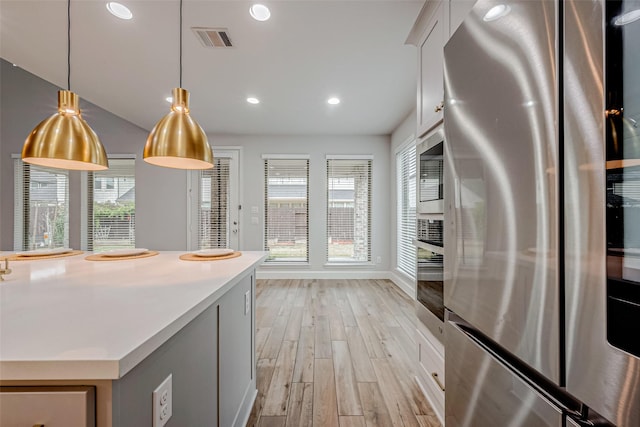 kitchen with light wood-style flooring, recessed lighting, stainless steel appliances, visible vents, and hanging light fixtures