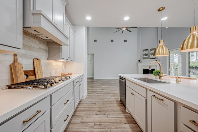 kitchen featuring appliances with stainless steel finishes, light countertops, a sink, and custom exhaust hood