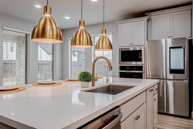 kitchen with stainless steel appliances, light countertops, white cabinetry, pendant lighting, and a sink