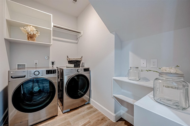 laundry room featuring laundry area, washing machine and clothes dryer, light wood-style flooring, and baseboards