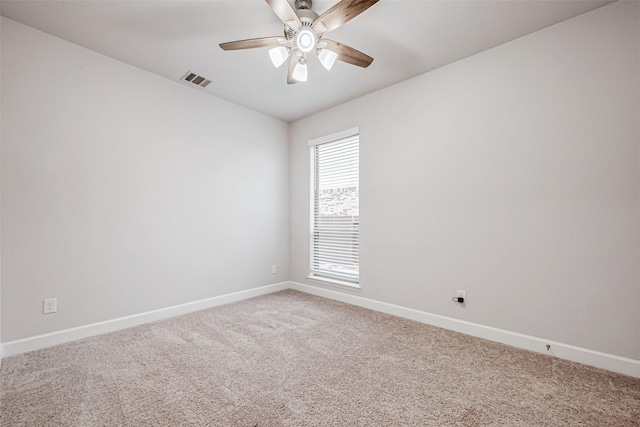 spare room featuring baseboards, visible vents, a ceiling fan, and light colored carpet