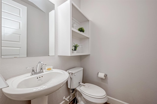 bathroom featuring a sink, toilet, and baseboards