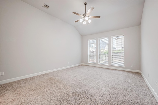 spare room featuring light colored carpet, a ceiling fan, baseboards, vaulted ceiling, and visible vents