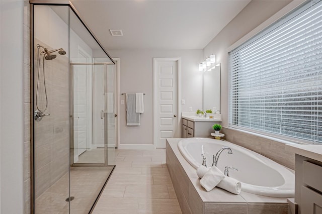 bathroom with a stall shower, a garden tub, plenty of natural light, and vanity