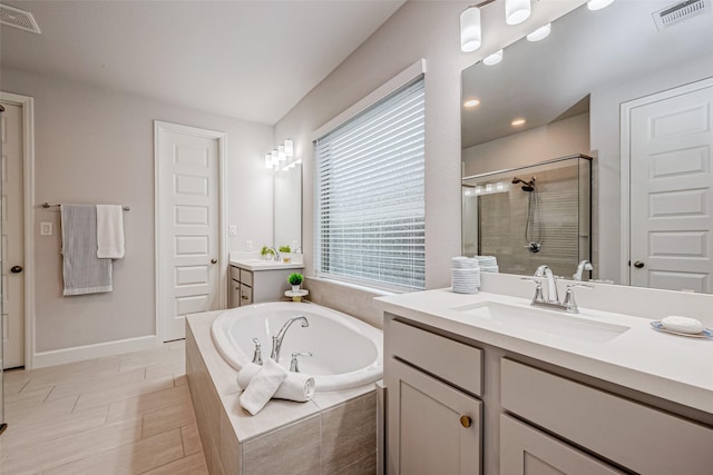 bathroom with a garden tub, a shower stall, visible vents, and a sink