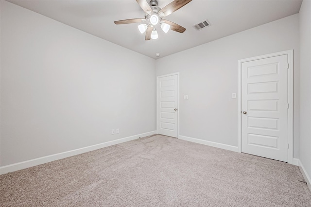 spare room with light colored carpet, visible vents, ceiling fan, and baseboards