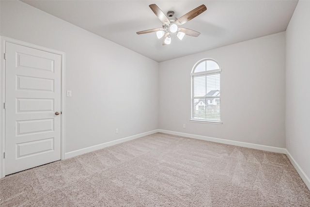 carpeted spare room featuring ceiling fan and baseboards