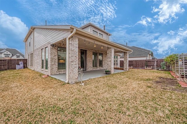 rear view of property featuring a yard, brick siding, and a patio