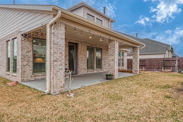 back of property featuring a patio, a yard, fence, and brick siding