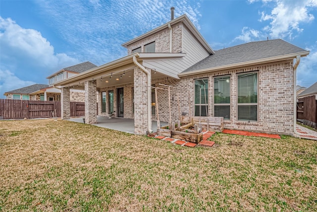 rear view of house featuring a patio, a yard, a fenced backyard, and brick siding