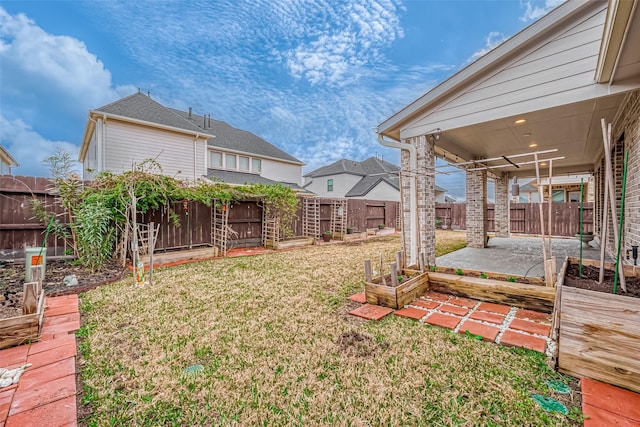 view of yard featuring a patio, a fenced backyard, and a vegetable garden