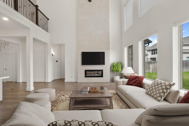 living room with a tiled fireplace, a towering ceiling, and dark hardwood / wood-style floors