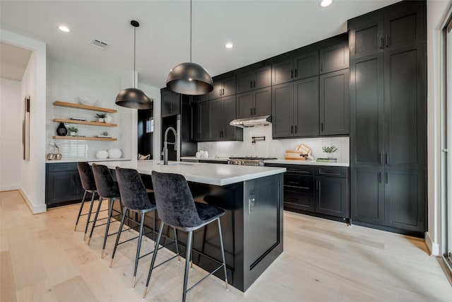 310 E 27th St, Houston, TX 77008 - kitchen with light wood-type flooring, under cabinet range hood, visible vents, and light countertops