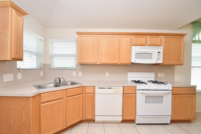 kitchen with sink, white appliances, light tile patterned floors, light brown cabinetry, and vaulted ceiling