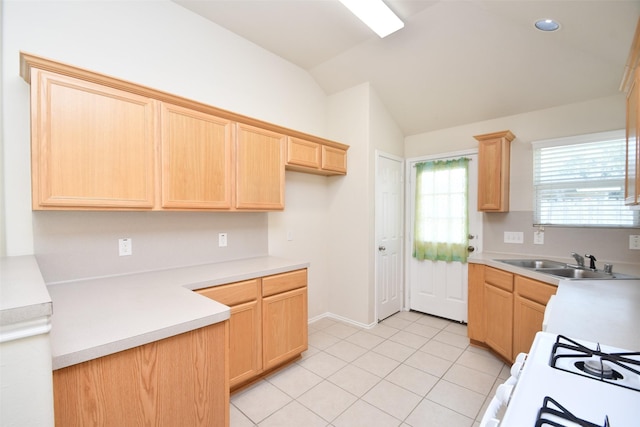 kitchen with lofted ceiling, sink, white range with gas stovetop, light tile patterned flooring, and light brown cabinetry