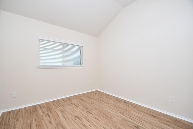 empty room with vaulted ceiling and light hardwood / wood-style floors