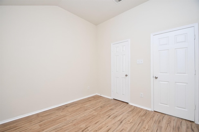 spare room with vaulted ceiling and light hardwood / wood-style floors