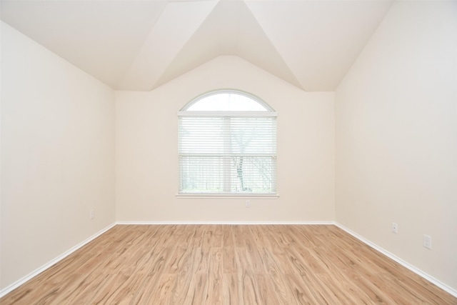 empty room with light hardwood / wood-style flooring and vaulted ceiling